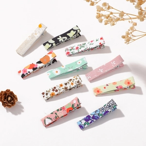 Flat lay of 10 assorted floral cotton linen hair clips for girls in a vintage forest style