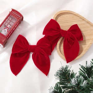 Close-up of two large red velvet bows with long tails on a festive holiday background