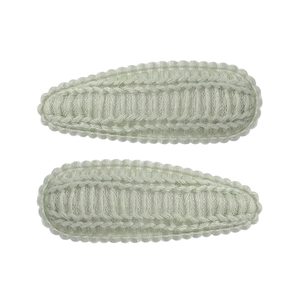 Detail of mint green drop-shaped knitted hair clips with fine crochet texture on white background