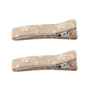 Detail of two beige embroidered linen flower hair clips with handmade fabric wrapping