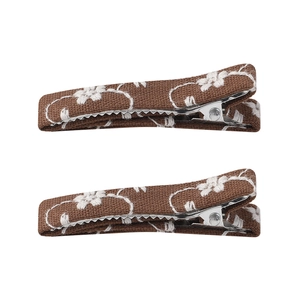 Detailed close-up of brown fabric hair clips with delicate white floral embroidery