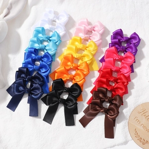 Set of colorful satin bow hair clips for girls in various candy colors on white fabric