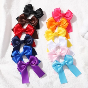 Flat lay of colorful satin ribbon bow hair clips set on a textured white fabric background