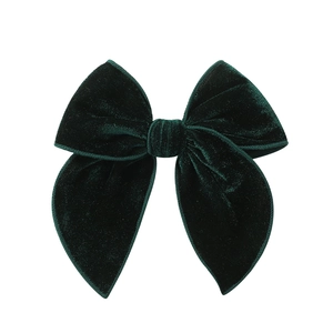 Detail view of dark green velvet bow hair clip with vintage academic style texture