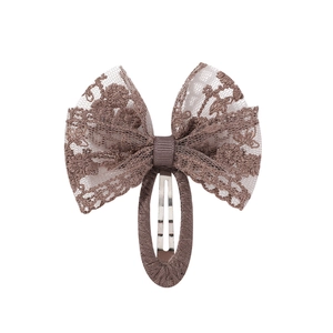 Détail d'une barrette à cheveux en dentelle florale brune avec ruban et base recouverte