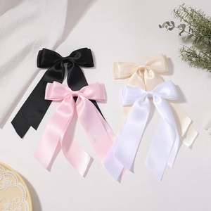 Détails de quatre pinces à cheveux en satin aux tons noir, rose et blanc sur tissu doux