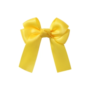 Close-up detail of a bright yellow satin bow hair clip with fine silk texture and elegant ribbons
