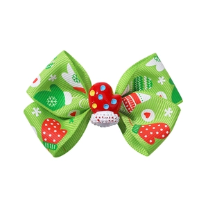 Detailed view of a green Christmas ribbon bow hair clip with 3D red glove ornament
