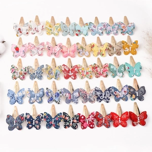 Flat lay of 40 butterfly hair clips with various floral prints and pearl centers