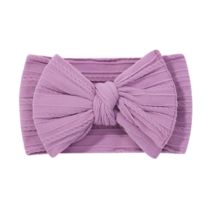 Close-up of purple cable-knit baby headband with a large decorative bow and soft texture
