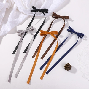 Detail showing various colors of long tassel ribbon bow hair clips in a stylish arrangement