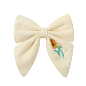 Détail d'un nœud à cheveux crème avec broderie de tournesol et texture de tissu en coton