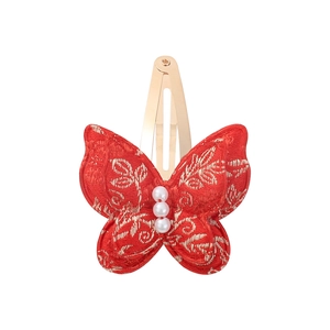 Detailed close-up of red fabric butterfly hair clip with gold embroidery and white pearls
