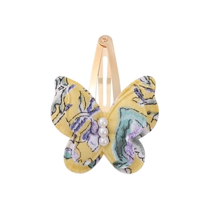 Detailed macro view of yellow floral fabric butterfly clip with three white pearls decoration