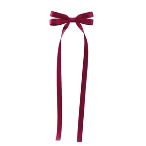 Detail of elegant wine red satin bow hair clip with long ribbons and smooth texture