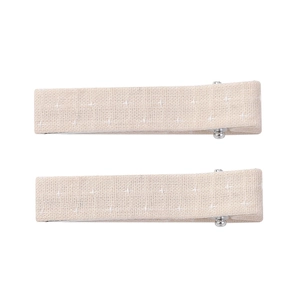 Détail de barrettes en tissu avec texture coton lin et motifs de points de croix blancs