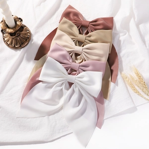 Elegant satin bow hair clips set in five colors with long ribbons on white linen