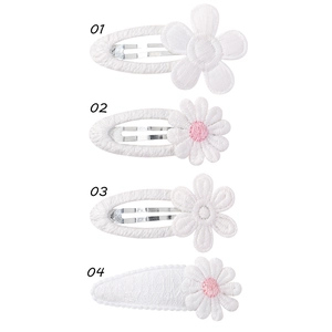 Détail de quatre barrettes à fleurs blanches brodées avec cœurs roses pour filles