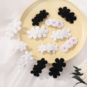 Détail de pinces à cheveux brodées à la main en forme de tournesol noires et blanches