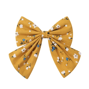 Detail shot of a ginger yellow floral cotton bow hair clip with small blue and white flower prints