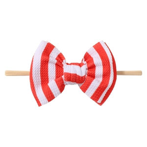 Detail view of baby bow headband featuring red and white striped waffle fabric and nylon strap