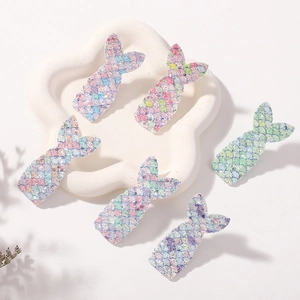Detailed view of shimmering mermaid tail glitter hair clips on a white display tray