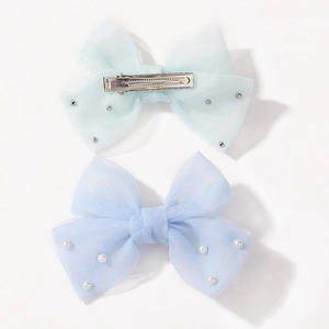 Détail de deux barrettes à nœuds en tulle vert et bleu avec perles et pinces crocodile en métal