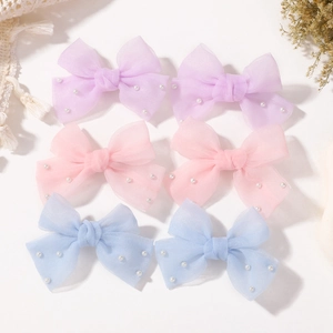 Vue détaillée de six pinces à nœud en tulle perlé en violet, rose et bleu pastel