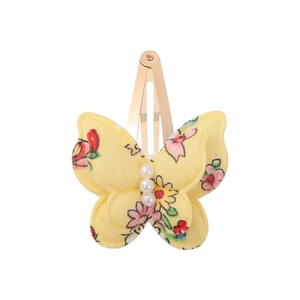 Detailed view of yellow floral butterfly hair clip with white pearls and golden metal BB base