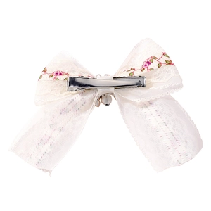 Dettaglio del fermaglio per bambini in pizzo con ricamo floreale e clip a coccodrillo in metallo