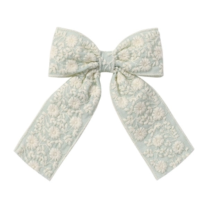 Détail d'un nœud à cheveux vert menthe avec broderie marguerite et rubans en dentelle