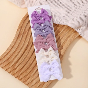 Dettaglio di cinque fermagli per capelli a fiocco in tessuto a nido d'ape color pastello