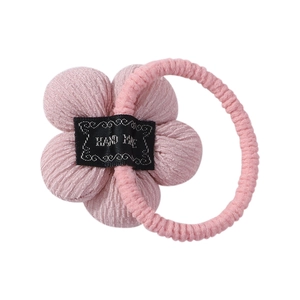 Detailed macro view of pink sunflower hair tie with hand made label and knitted texture
