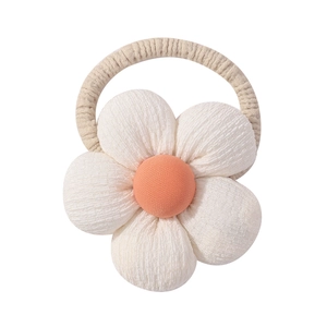 Close-up of linen fabric flower hair tie with cream petals and orange-pink center button