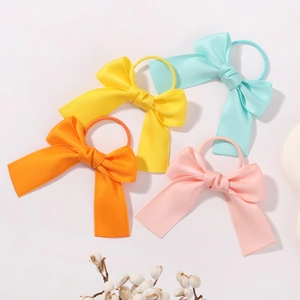 Detail of four colorful bow hair ties in yellow, blue, orange and pink polyester cotton