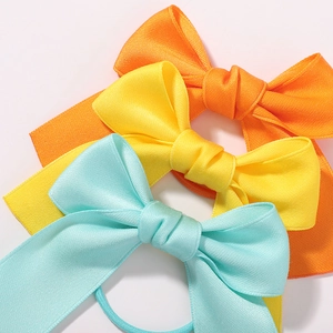 3-piece set of girls swallowtail bow hair ties in orange, yellow, and mint green ribbon