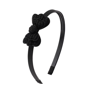 Detail of a black headband with a handmade crochet bow on a textured grosgrain ribbon wrap