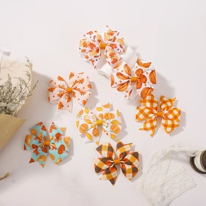 Detail shot of autumn hair bows with pumpkin and maple leaf patterns on a white background