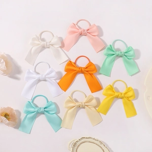 Flat lay of 8-piece set satin bow hair ties in assorted pastel colors for girls