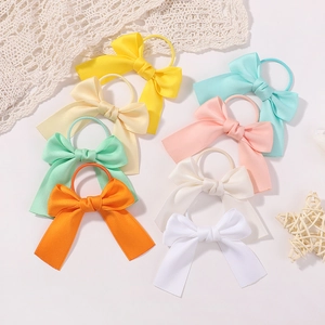Flat lay of 8 colorful satin bow hair ties for children with delicate lace and star decor
