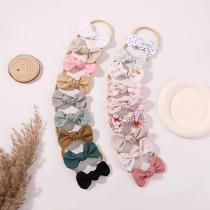 Set of baby bow headbands in various solid colors and patterns on neutral background