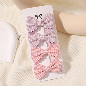 Detail view of four-piece plaid bow hair clips set on display card in warm soft tones