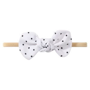 Close-up of baby headband featuring white and black polka dot bow with soft nylon band