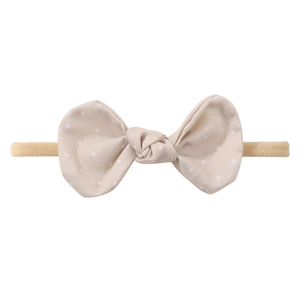 Detailed macro view of beige polka dot bow headband for babies with elastic nylon strap