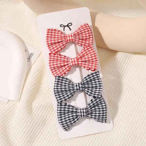 Detail of four-piece plaid bow hair clip set with red and black gingham fabric patterns