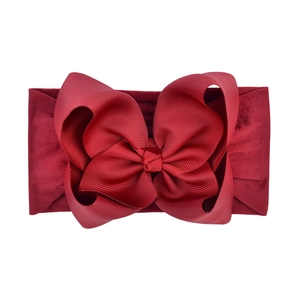 Macro detail of burgundy jacquard grosgrain bow and elastic nylon baby headband