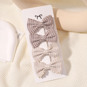 Detail of four gingham plaid bow hair clips for girls displayed on a white product card