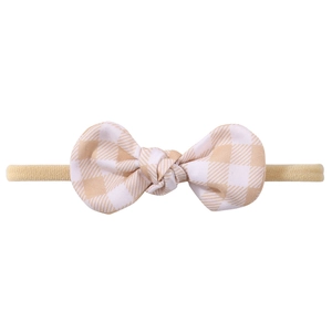 Detail eines Baby Stirnbands mit beigefarbener karierter Baumwollschleife und Band