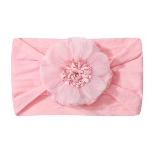 Dettaglio di una fascia rosa per neonati in nylon morbido con un grande fiore fatto a mano