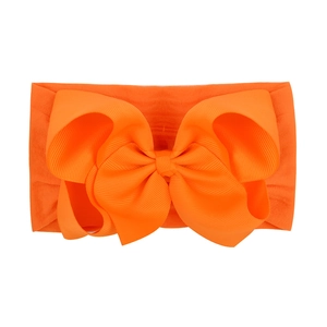 Macro view of bright orange jacquard nylon headband with large grosgrain ribbon bow
